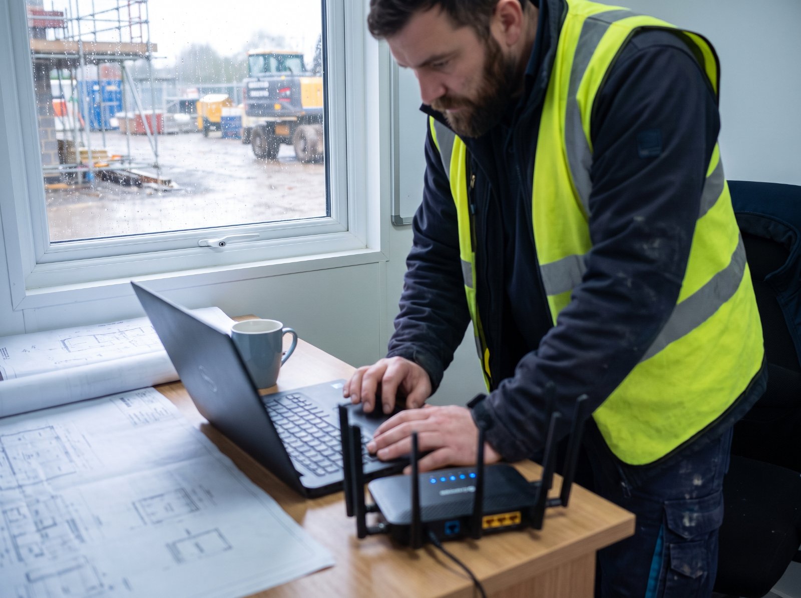 Site manager working beside a 4G/5G router in a site office